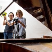 Mike Lee, Ph.D. ’15 and Elizaveta Zabelina ’24 take pictures of a piano