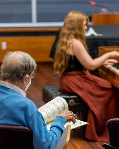 Teacher looks at score while student is playing